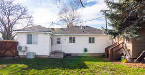 Rear view of house featuring entry steps, a shingled roof, a yard, and a gate