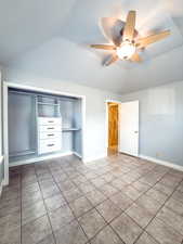 Unfurnished bedroom with lofted ceiling, light tile patterned flooring, ceiling fan, and a closet