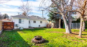 Back of property featuring a gate, a fenced backyard, a shingled roof, an outdoor fire pit, and entry steps