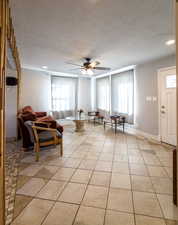 Living room with a textured ceiling, ceiling fan, light tile patterned floors, and recessed lighting