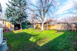 Fenced backyard with a fire pit and a storage unit