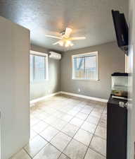 Unfurnished dining area with a textured ceiling, ceiling fan, plenty of natural light, and light tile patterned flooring