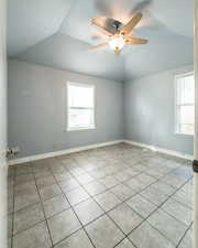 Spare room featuring a ceiling fan, light tile patterned floors, and lofted ceiling