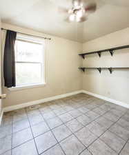 Spare room with a ceiling fan, light tile patterned floors, and lofted ceiling