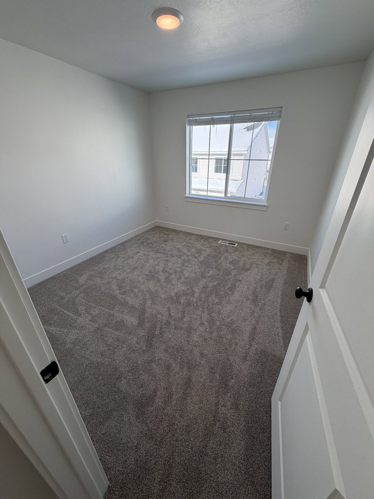 Empty room featuring dark colored carpet and baseboards