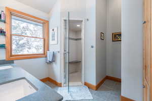 Full bath with double vanity, light tile patterned floors, and a stall shower