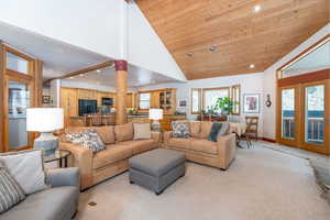Carpeted living area featuring recessed lighting, a vaulted wood ceiling, and french doors