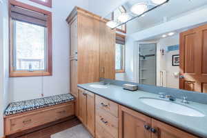 Bathroom featuring double vanity, dark tile patterned flooring, a tile shower, and healthy amount of natural light