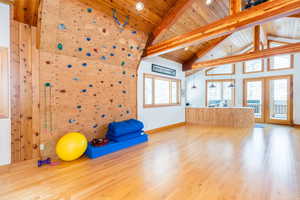 Workout room with french doors, light wood-type flooring, and a high wooden beamed ceiling