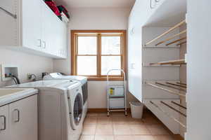 Laundry room with cabinet space, washer and dryer, and light tile patterned floors