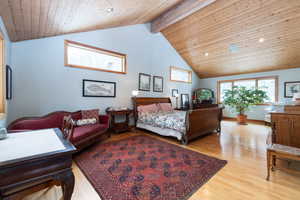 Bedroom with a high wood beamed ceiling, light wood-style floors, multiple windows, and recessed lighting