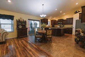 Dining area with suspended lighting, lofted ceiling, and dark wood-style floors
