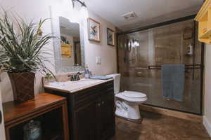 Bathroom with vanity, a shower stall, and a textured ceiling