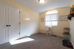 Empty room with lofted ceiling and carpet flooring
