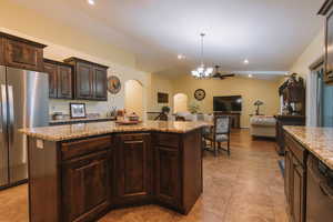 Kitchen with dark wood finish cabinets, lofted ceiling, freestanding refrigerator, open floor plan, and a kitchen island