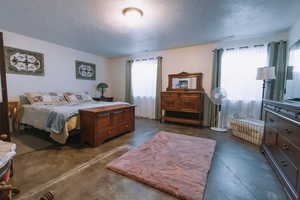Bedroom featuring finished concrete flooring and a textured ceiling