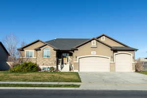 View of front of property with an attached garage, driveway, stucco siding, a front yard, and brick siding