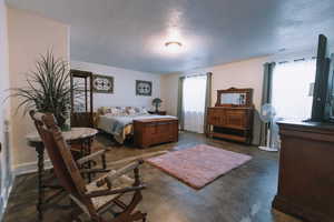 Bedroom with concrete floors and a textured ceiling