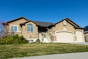 View of front of property featuring an attached garage, a front lawn, stucco siding, concrete driveway, and brick siding