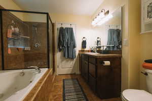 Bathroom featuring vanity, a shower stall, a jetted tub, and dark tile patterned floors