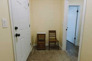 Hallway featuring dark colored carpet and baseboards