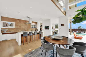 Dining area with light wood finished floors, recessed lighting, and a high ceiling