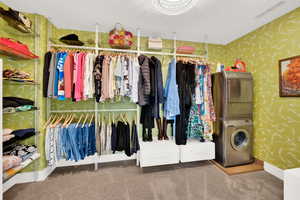 Walk in closet featuring stacked washer and clothes dryer and carpet