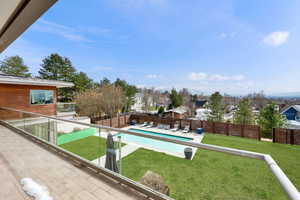 View of pool with a fenced backyard, a residential view, patio surround, and a balcony