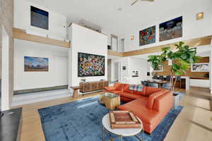 Living area featuring light wood-style floors, a ceiling fan, and a high ceiling