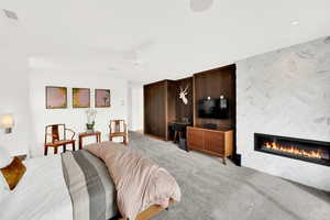 Bedroom featuring light colored carpet, a fireplace, and ceiling fan