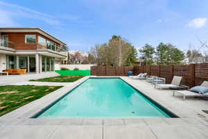 View of pool with patio surround, a fenced backyard, and a balcony