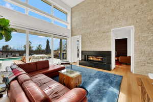 Living area with a high ceiling, a stone fireplace, and light wood-type flooring