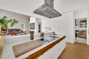 Kitchen featuring modern cabinets, white cabinetry, island exhaust hood, and black electric stovetop