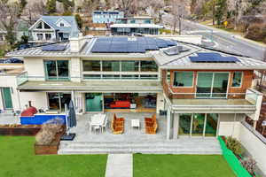 Back of property featuring a patio area, a standing seam roof, outdoor dining space, solar panels, and a yard