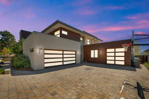 Modern home featuring decorative driveway, an attached garage, and stucco siding