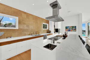 Kitchen with plenty of natural light, modern cabinets, white cabinetry, island exhaust hood, and tile walls