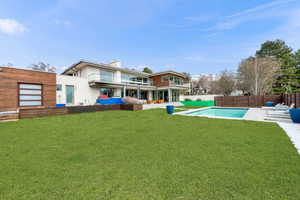 Back of house featuring a patio area, a fenced backyard, a chimney, and a balcony