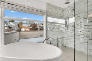 Bathroom with a shower stall, a freestanding bath, light tile patterned floors, and tile walls
