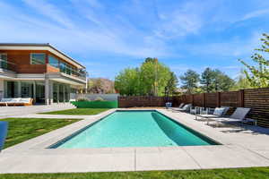View of swimming pool with patio surround, a balcony, and a fenced backyard