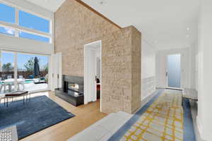 Living room featuring a glass covered fireplace, a high ceiling, and light wood-style floors