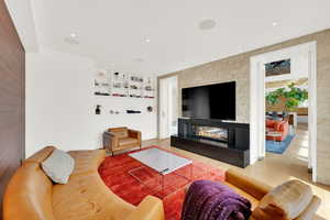 Living room with a fireplace, built in shelves, light wood-style floors, and recessed lighting