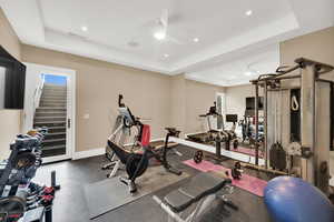 Exercise room featuring a raised ceiling, ceiling fan, and recessed lighting