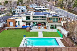 Rear view of property featuring a fenced backyard, a patio, roof mounted solar panels, stucco siding, and a residential view