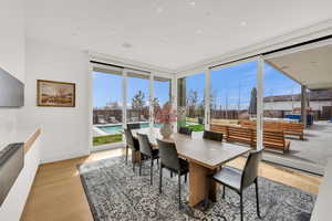 Dining room with floor to ceiling windows and light wood-style flooring