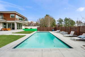 View of swimming pool featuring patio surround, a fenced backyard, and a balcony