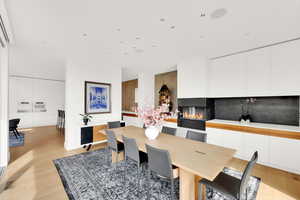 Dining room with light wood-style flooring, a glass covered fireplace, and recessed lighting