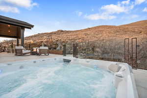 View of pool with a mountain view, patio surround, outdoor furniture, and a hot tub