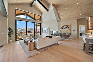 Living area featuring a mountain view, light wood-type flooring, recessed lighting, and a high wooden beamed ceiling