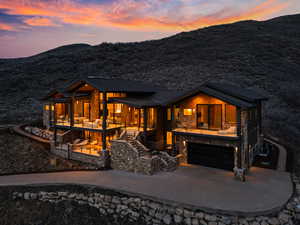 Back of house with stone siding, an attached garage, a mountain view, and driveway