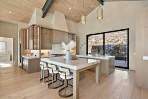 Kitchen with light wood-style flooring, a high wood beamed ceiling, a kitchen breakfast bar, hanging light fixtures, and open shelves